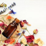 Various bright medicinal herb plant on wooden plate, essential oil extract bottle, top view.