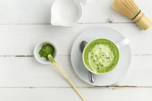 Matcha latte cup on white background from above. This latte is a delicious way to enjoy the energy boost & healthy benefits of matcha. Matcha is a powder of green tea leaves packed with antioxidants.